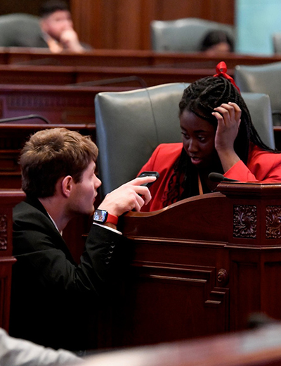 Two students speak to each other on the Illinois House of Representatives floor.